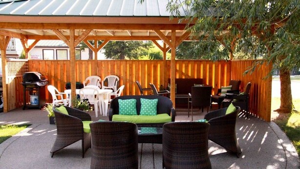 An outdoor patio area with wicker furniture, a grill, and a covered seating area. - Crystal Springs Lodge (Radium Hot Springs)