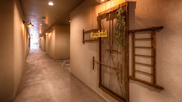 A hallway with a wooden door labeled "thankful," a ladder, and a hanging plant.