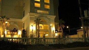 A building with a symmetrical facade, arched windows, and a balcony with railings. - Rafael Mansion Bangkok Airport (Bang Phli)