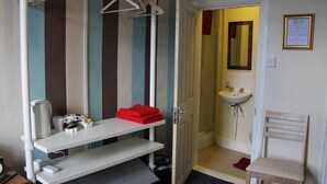 Un baño pequeño y funcional con lavamanos, espejo y una silla.