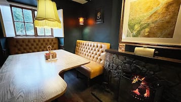 Una habitación acogedora con una mesa de madera, un banco acolchado, una chimenea y un mapa en la pared.