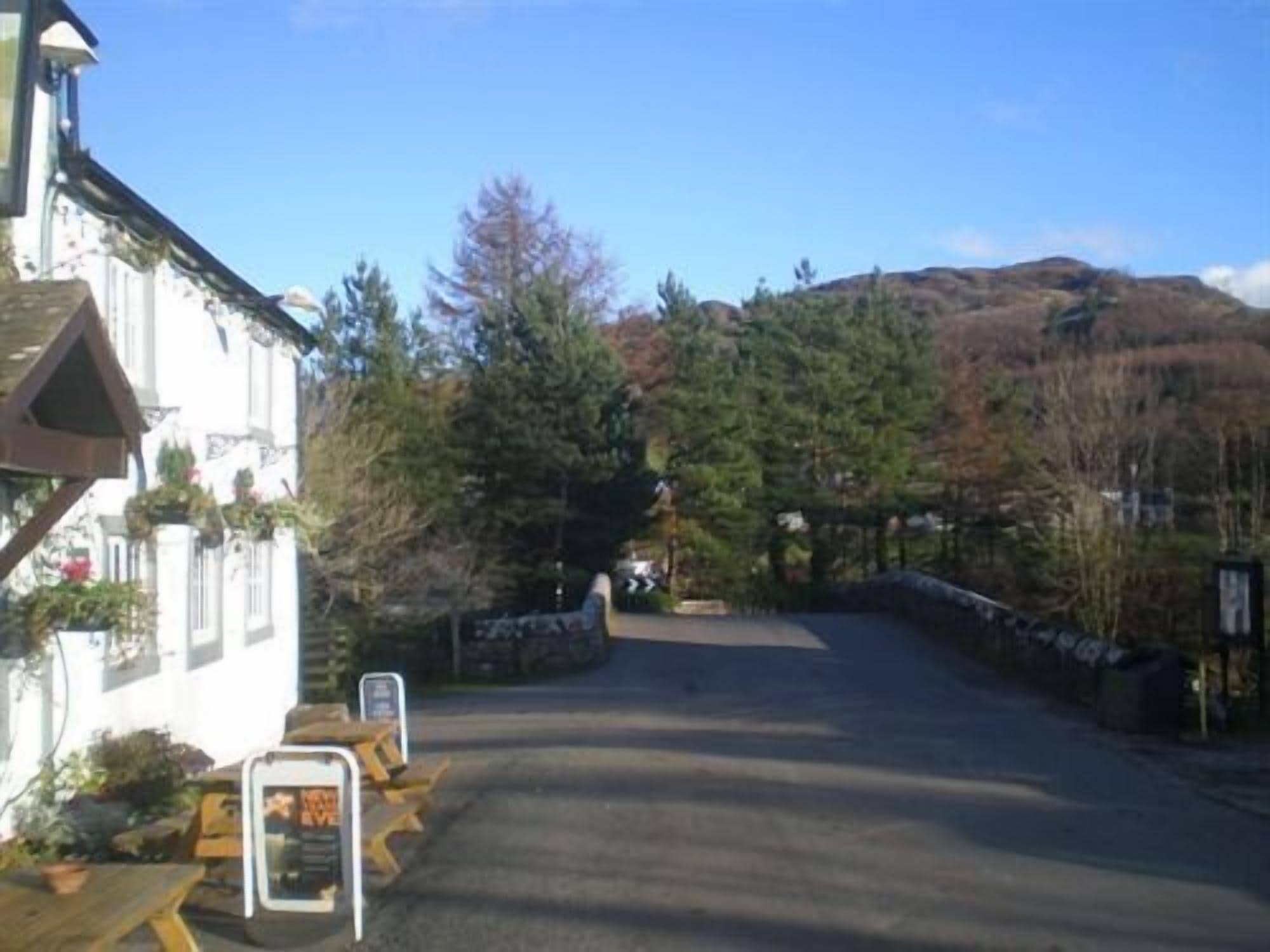 A white building with a wooden porch, a signboard, and a mountain in the background.
