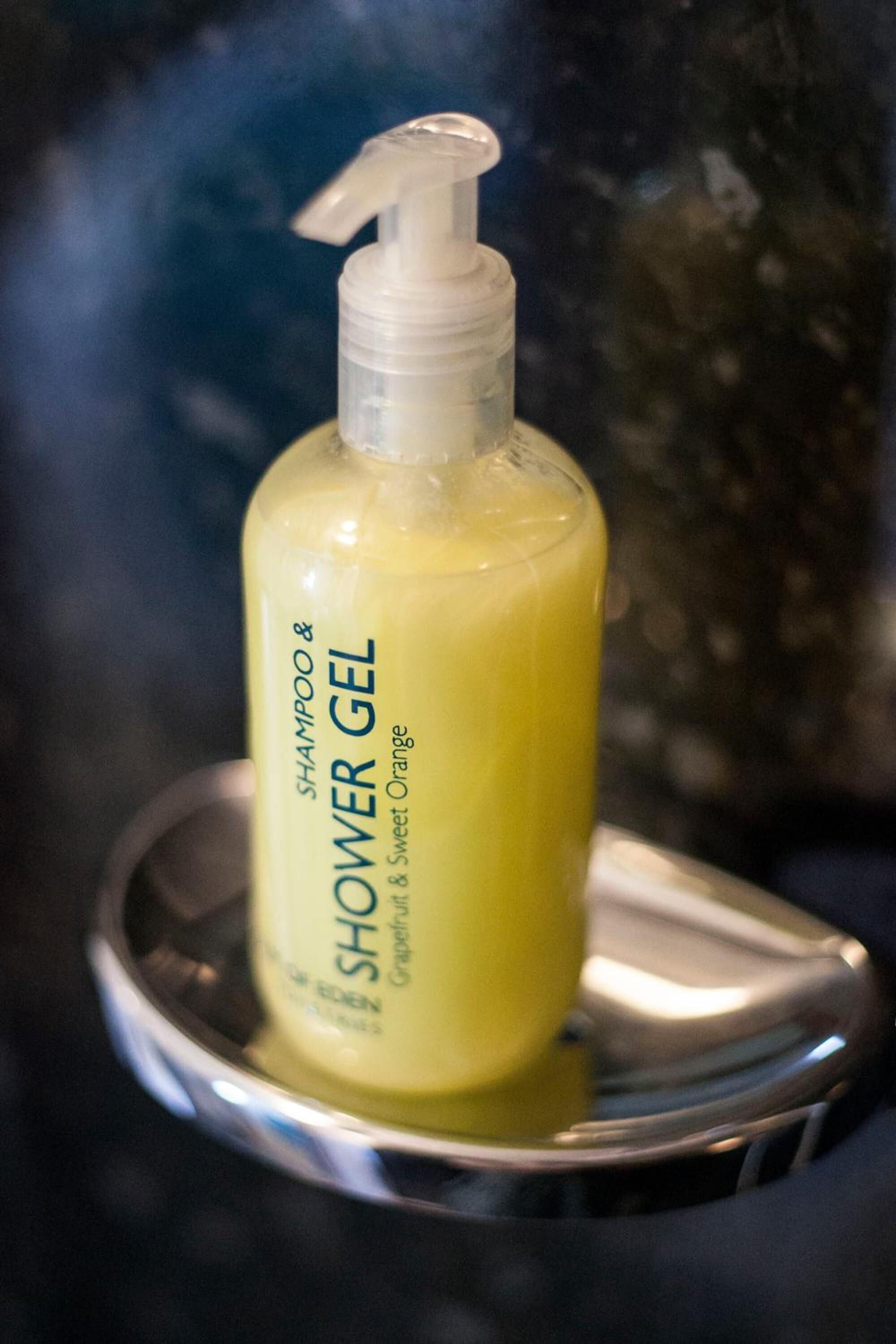 A bottle of shower gel on a metallic tray.