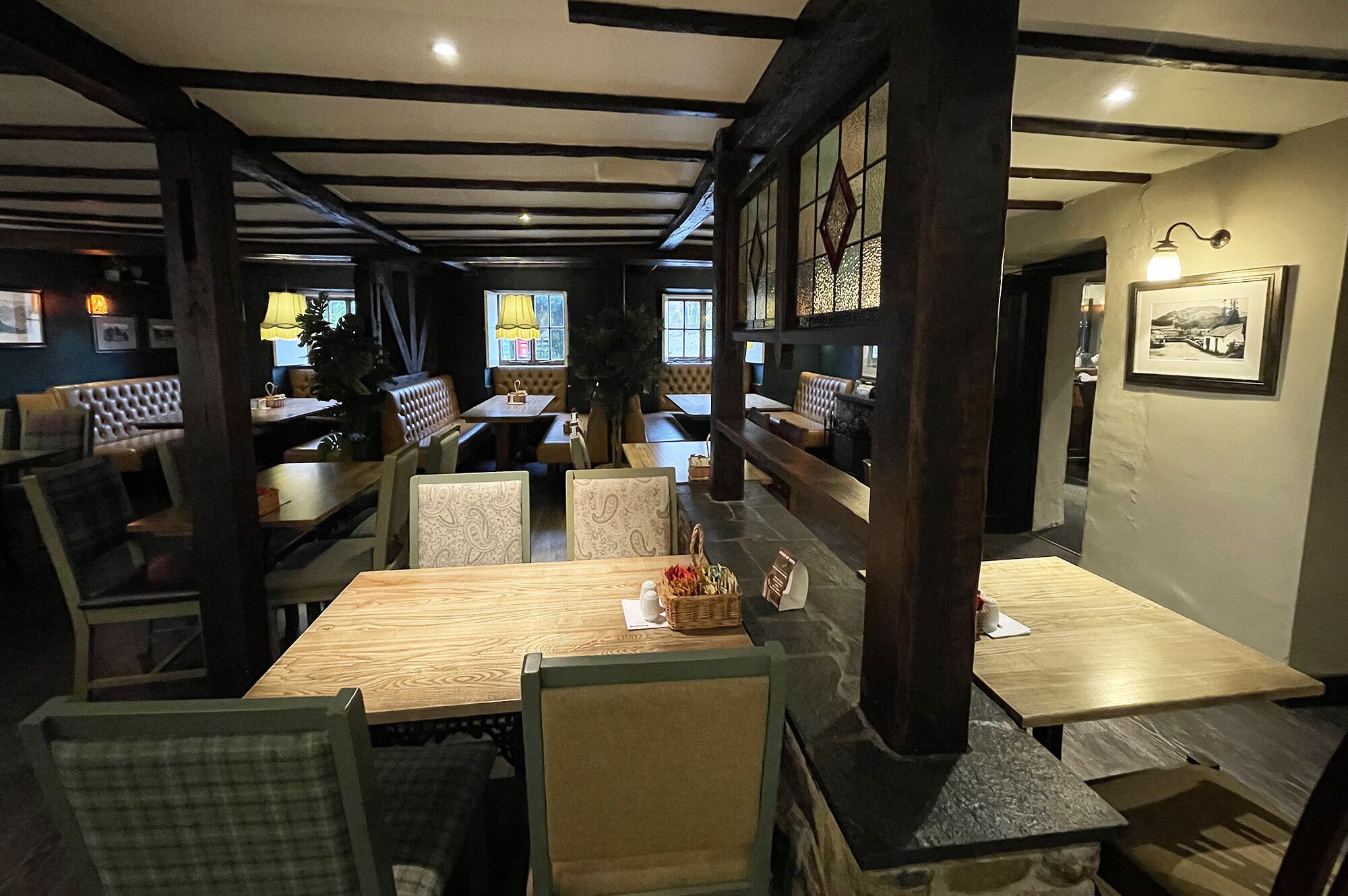 A restaurant interior with wooden tables and chairs, stone pillars, and a cozy ambiance.