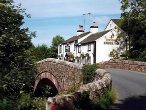 A stone bridge over a road leading to a white building labeled "Bridg" with a sign that reads "Inn."