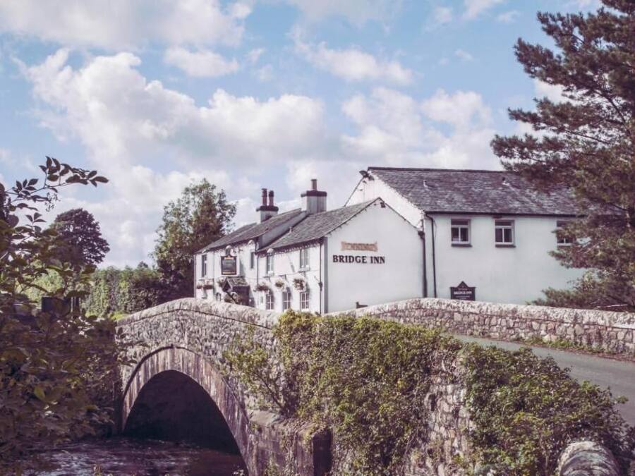A white building with a sign reading "Bridge Inn" across a stone bridge.