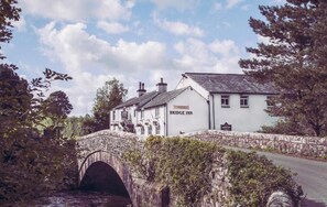 A white building with a sign reading "Bridge Inn" across a stone bridge. - The Bridge Inn (Holmrook)