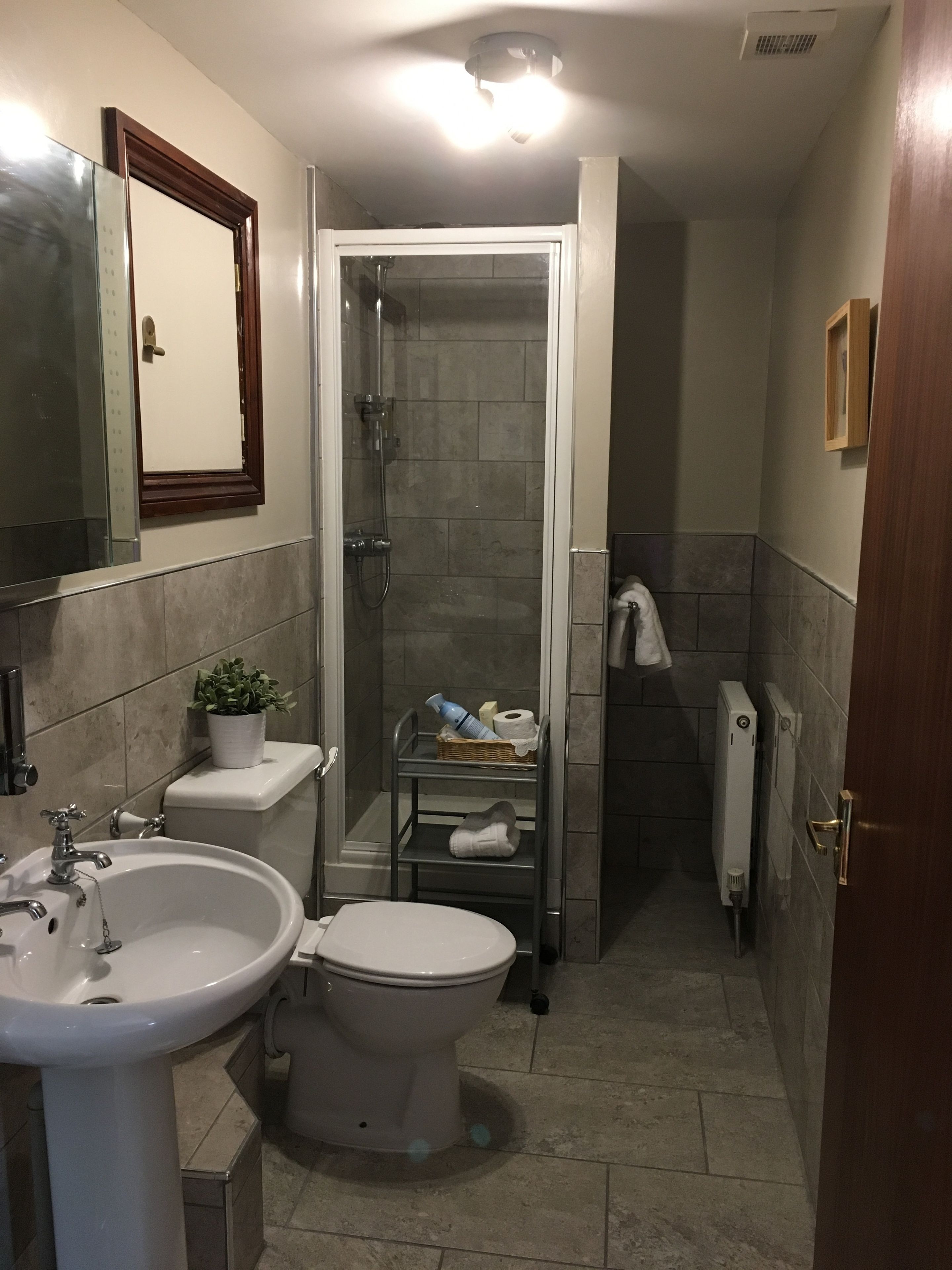A compact bathroom with a sink, toilet, and shower.