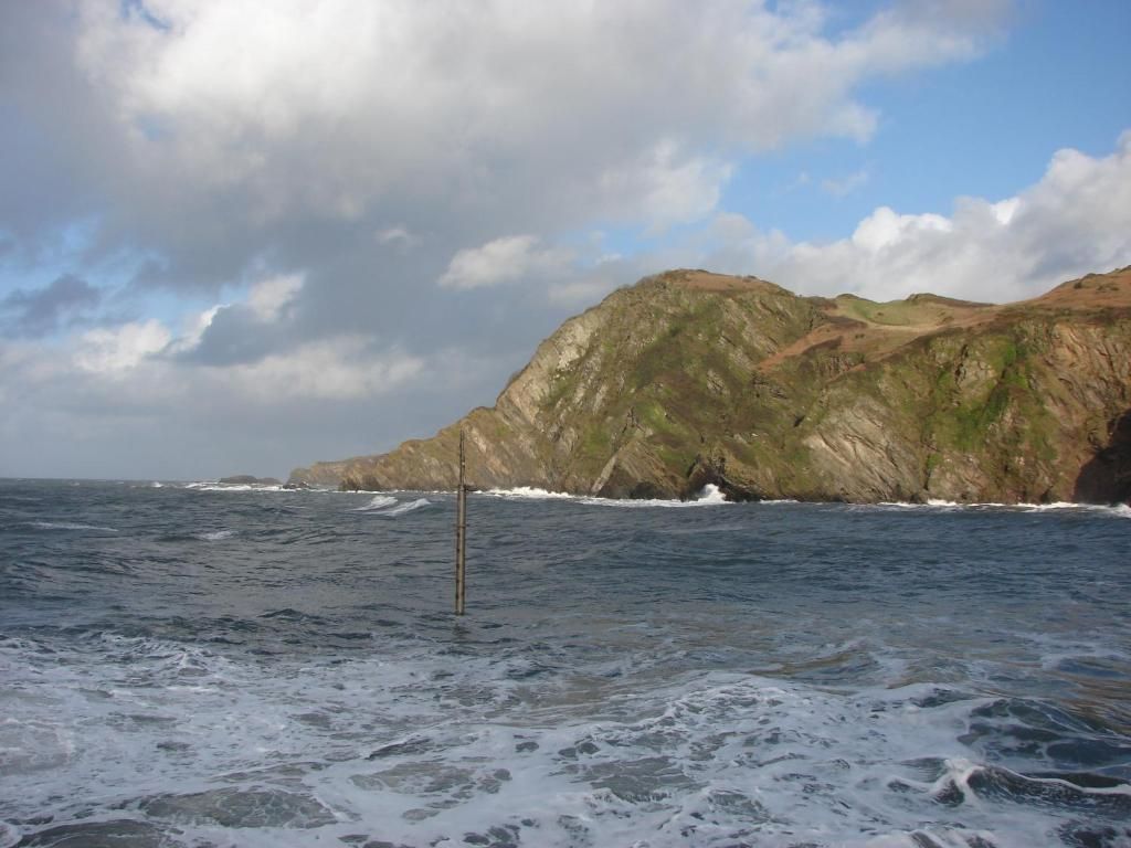 A coastal landscape with a rocky cliff and ocean waves.