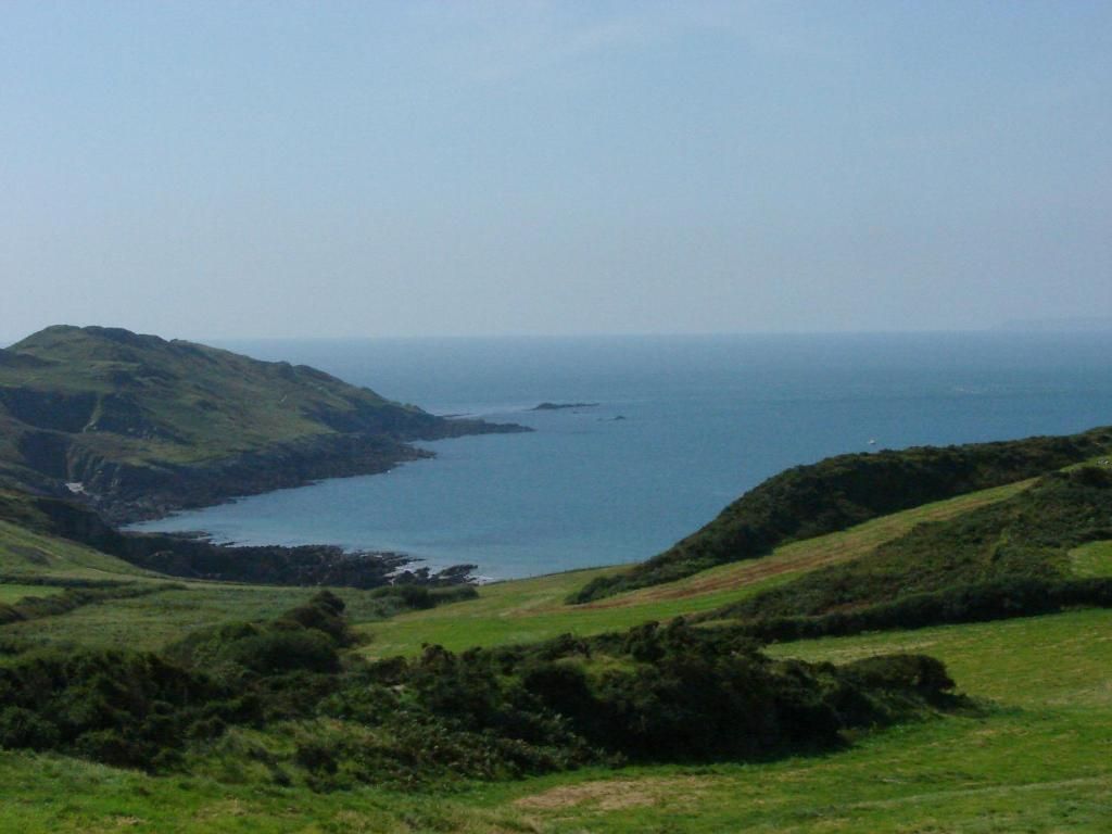 A coastal landscape with rolling hills and a body of water.
