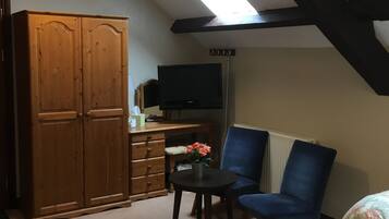 Ein Schlafzimmer mit Bett, Stuhl, Schreibtisch, Kleiderschrank und Fernseher.