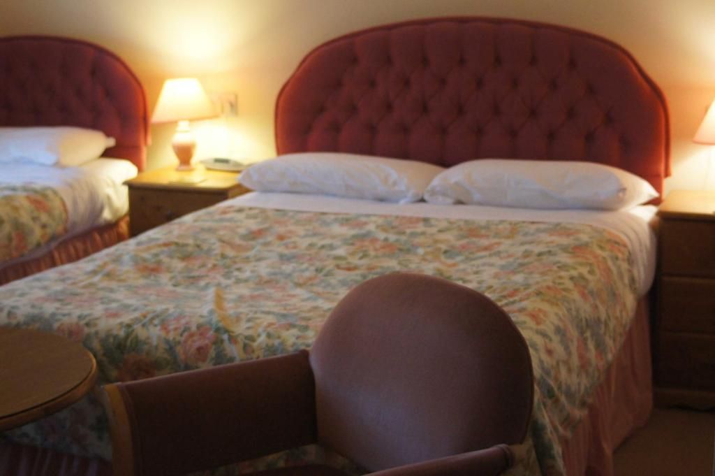 A hotel room with a large bed, a chair, and a bedside table.