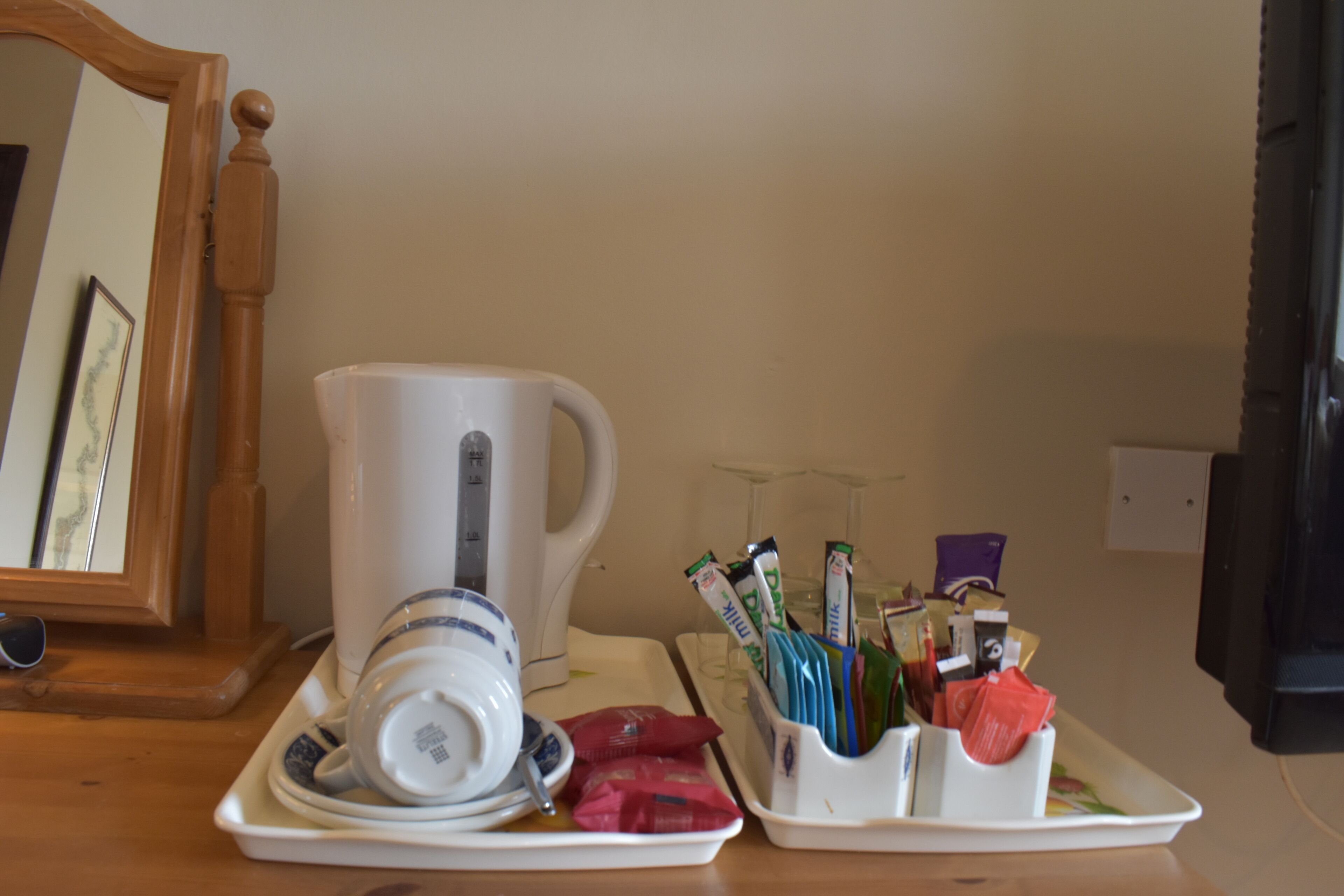 A kitchen counter with a coffee maker, a milk jug, and a tray with coffee pods and sugar packets.