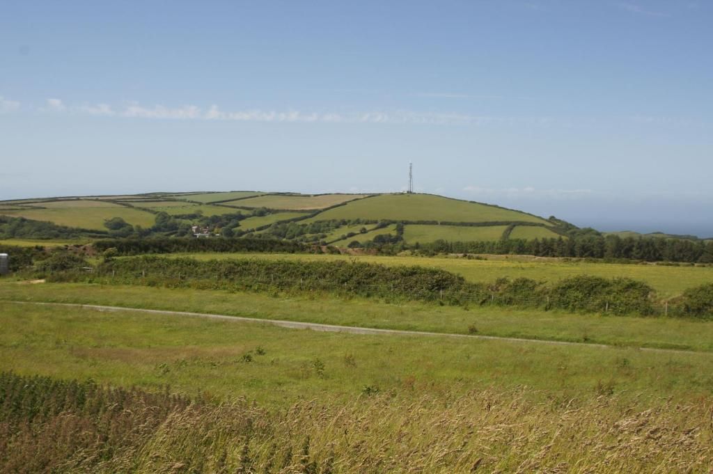 A rural landscape with rolling hills, a clear sky, and a distant communication tower.