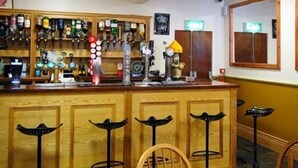 A bar area with wooden stools, a variety of liquor bottles, and a mirror on the wall. - Oakwell Holidays (Bridlington)