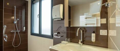 A modern bathroom with a large mirror, a sink, and a shower.