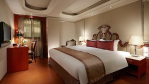 A hotel room with a large bed, a desk with a lamp, a chair, and a television. - Happiness Hotel (Taipei)