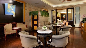 A hotel lobby with a seating area featuring sofas and armchairs, a round table with a vase of flowers, and a ceiling fan. - Happiness Hotel (Taipei)