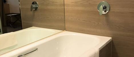 Un baño moderno con una bañera grande, paneles de madera y un espejo.