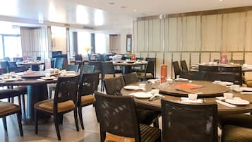 A dining area with multiple round tables and chairs, equipped with table settings and a menu stand.