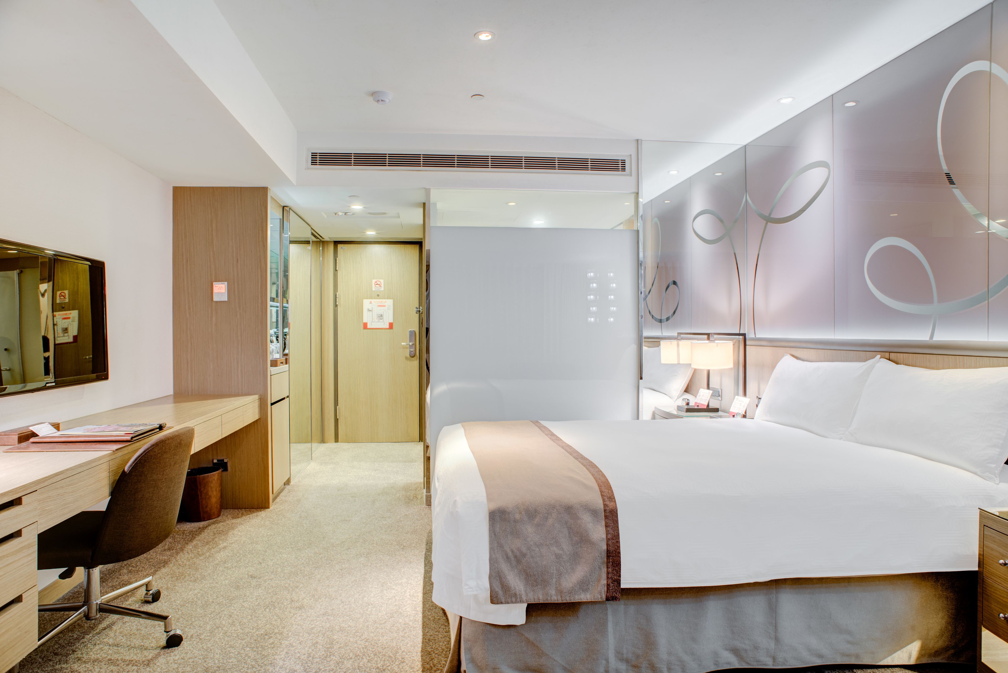 Une chambre d’hôtel avec un lit, un bureau, une chaise et un grand miroir.