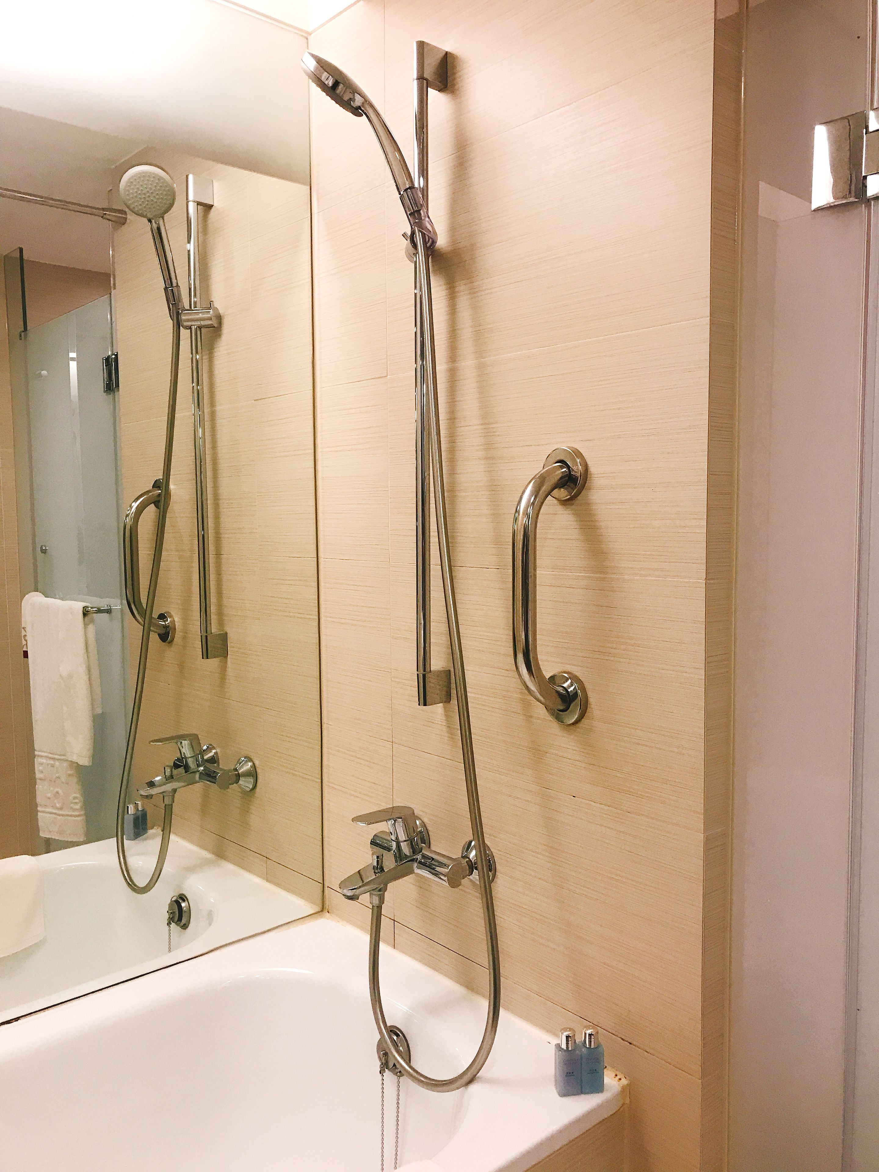 Un baño con bañera, ducha con cabezal de ducha de mano y grifo empotrado en la pared.