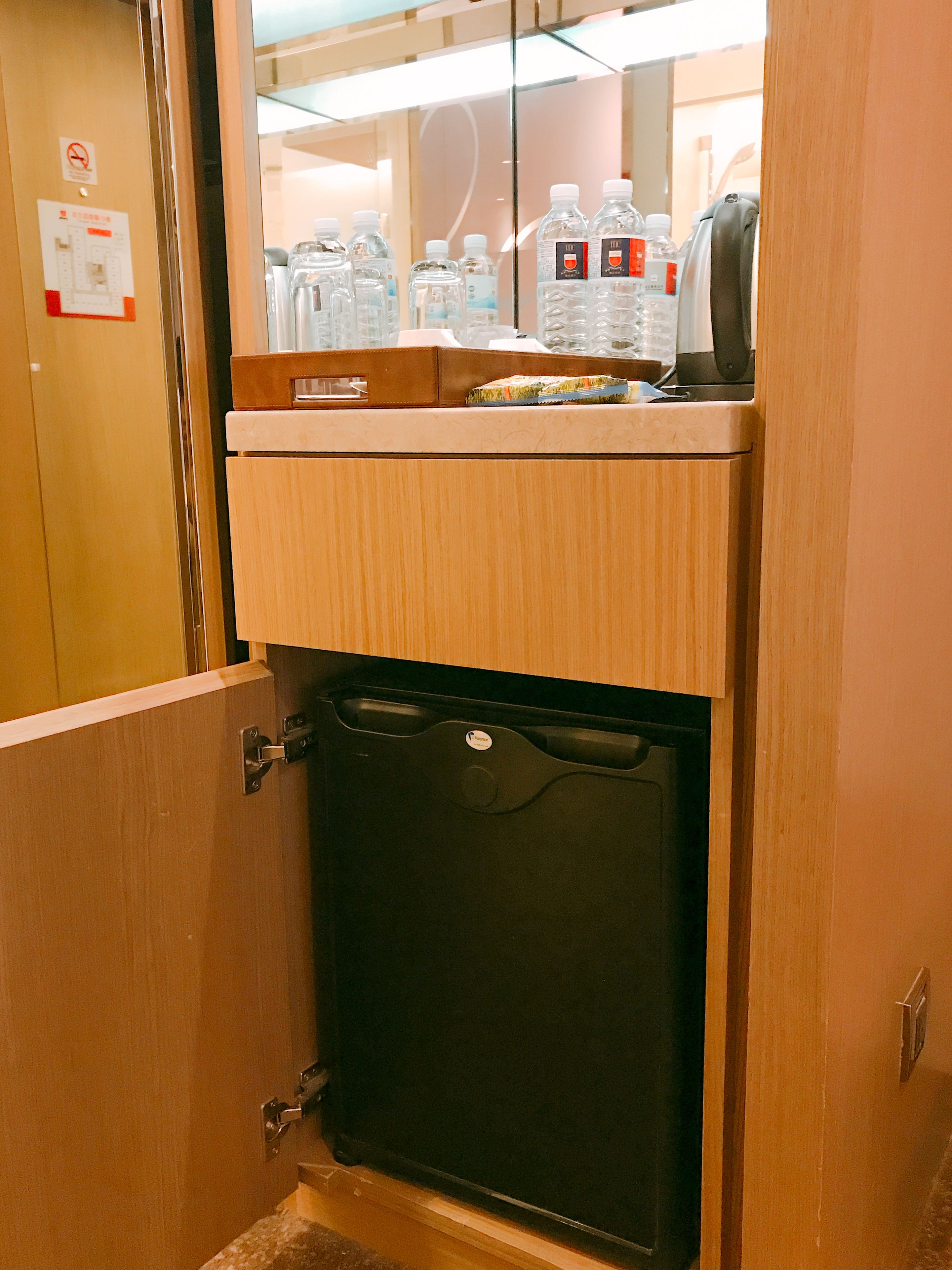 Habitación de hotel con minibar, refrigerador y espejo.
