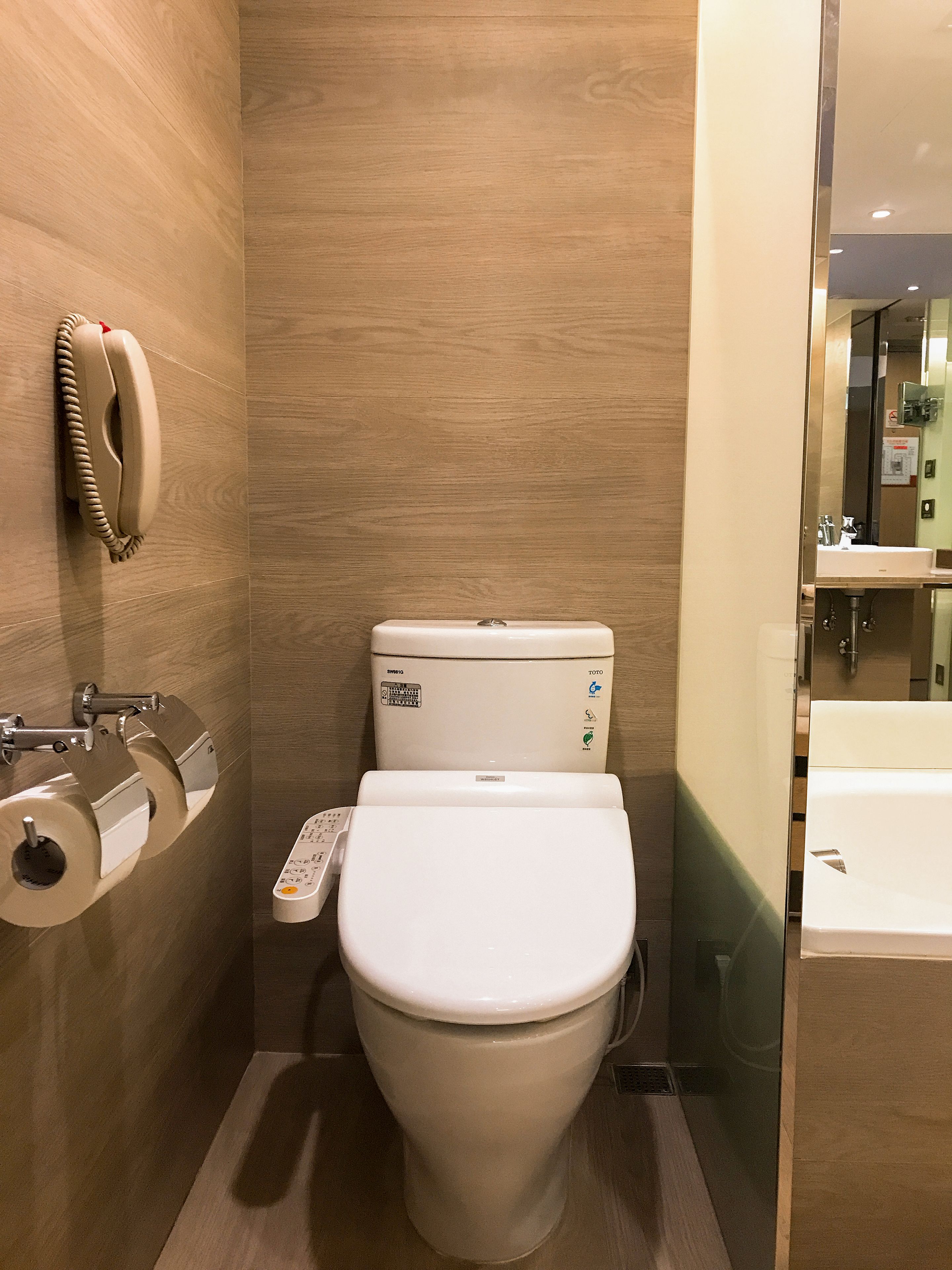 A compact bathroom with a toilet, a paper towel dispenser, and a hand dryer.