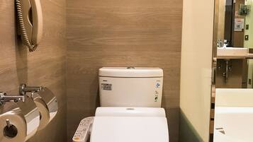 A compact bathroom with a toilet, a paper towel dispenser, and a hand dryer.