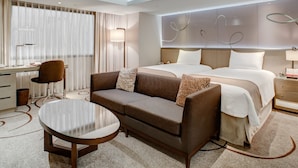 Une chambre d’hôtel moderne équipée d’un grand lit, d’un canapé, d’un bureau et d’une table ronde.