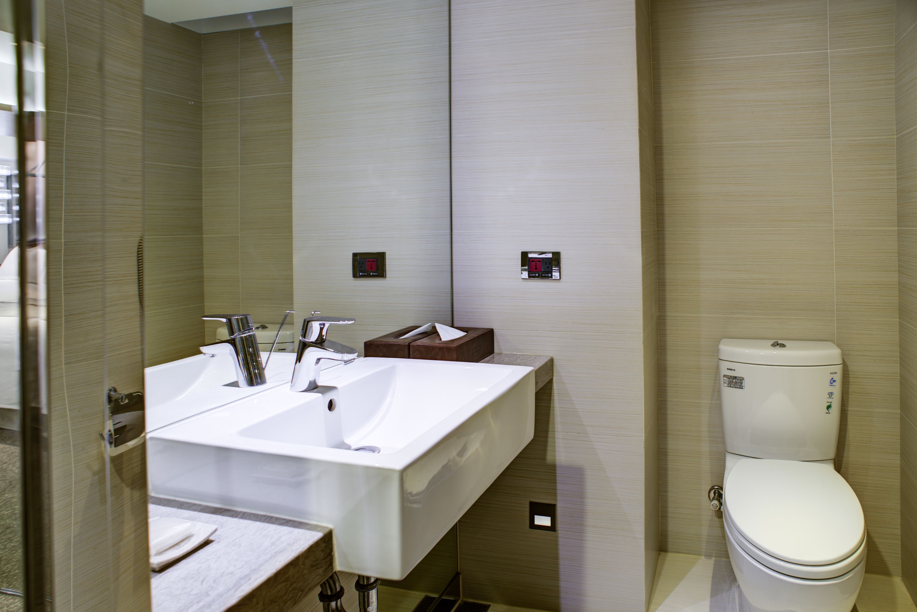 A modern bathroom with a large sink, a toilet, and a mirror.