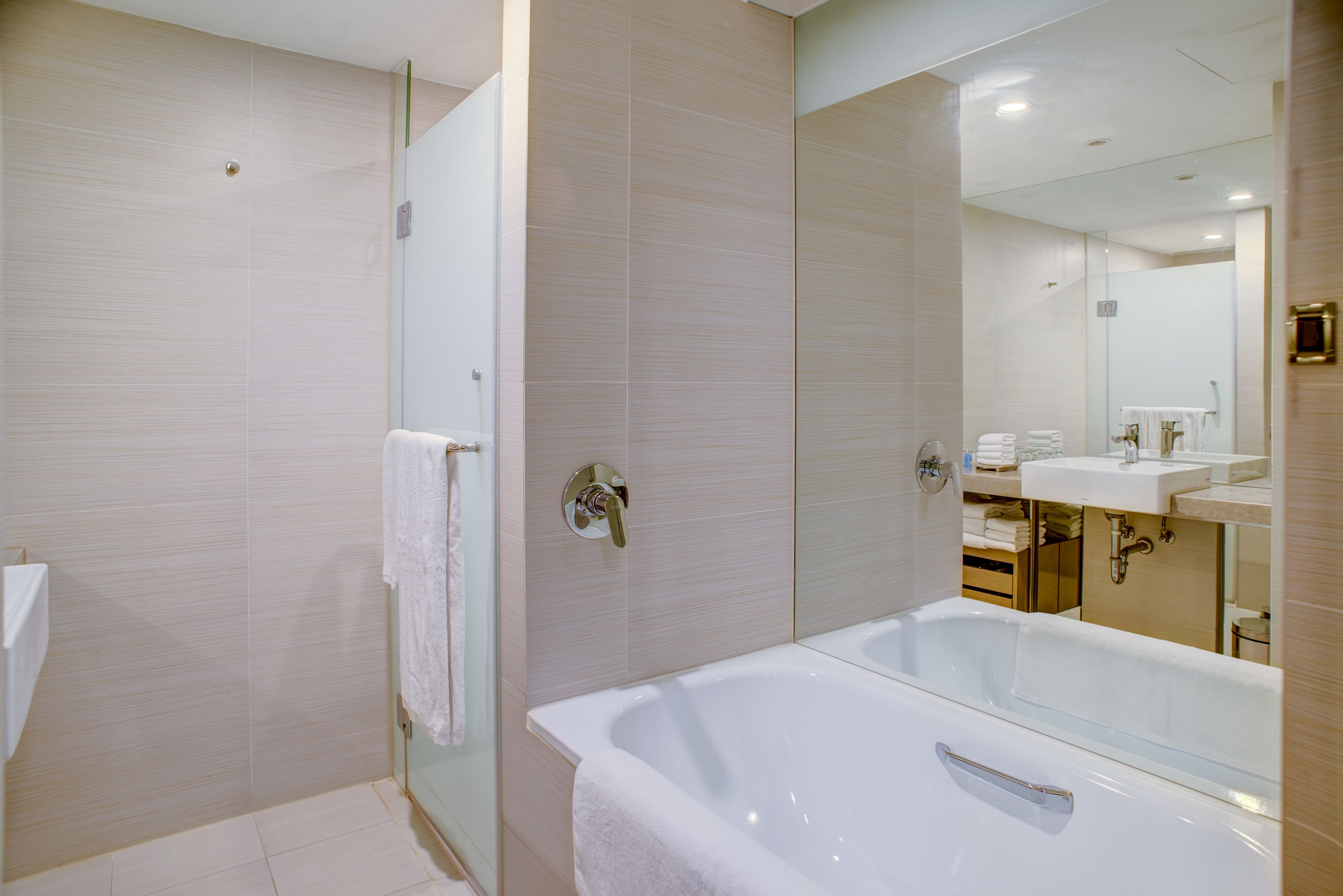 A modern bathroom with a glass-enclosed shower, a large bathtub, and a vanity with a mirror.