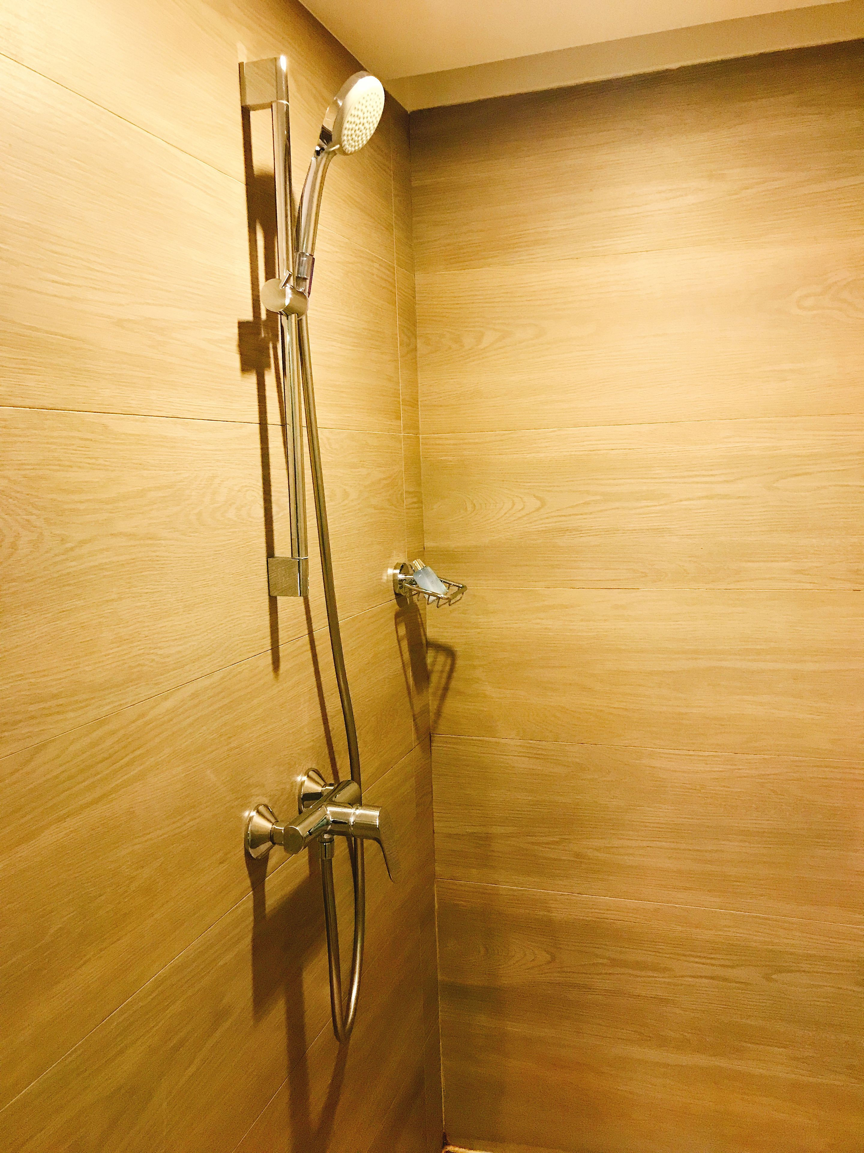 A shower with a handheld showerhead and a wall-mounted faucet.