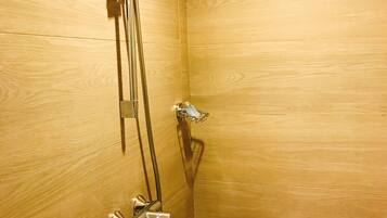 A shower with a handheld showerhead and a wall-mounted faucet.