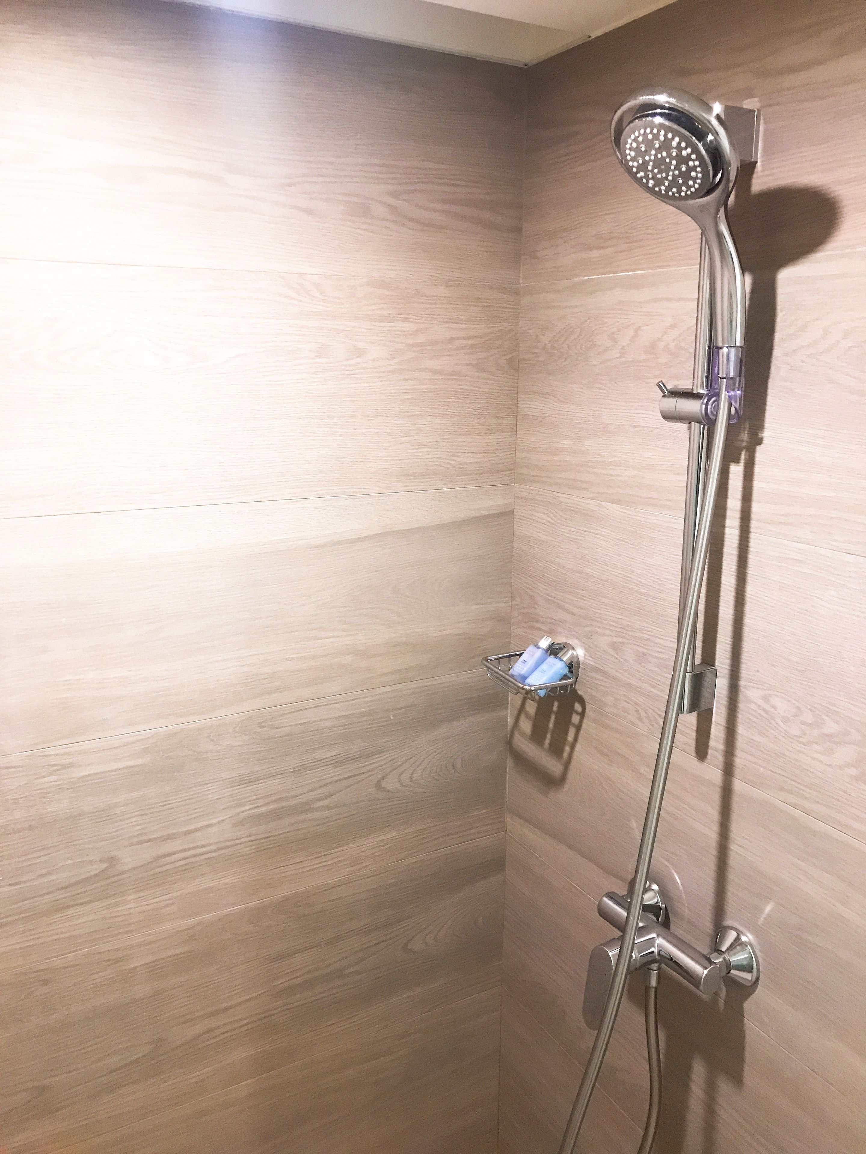 A shower with a handheld showerhead and a handheld shower attachment.