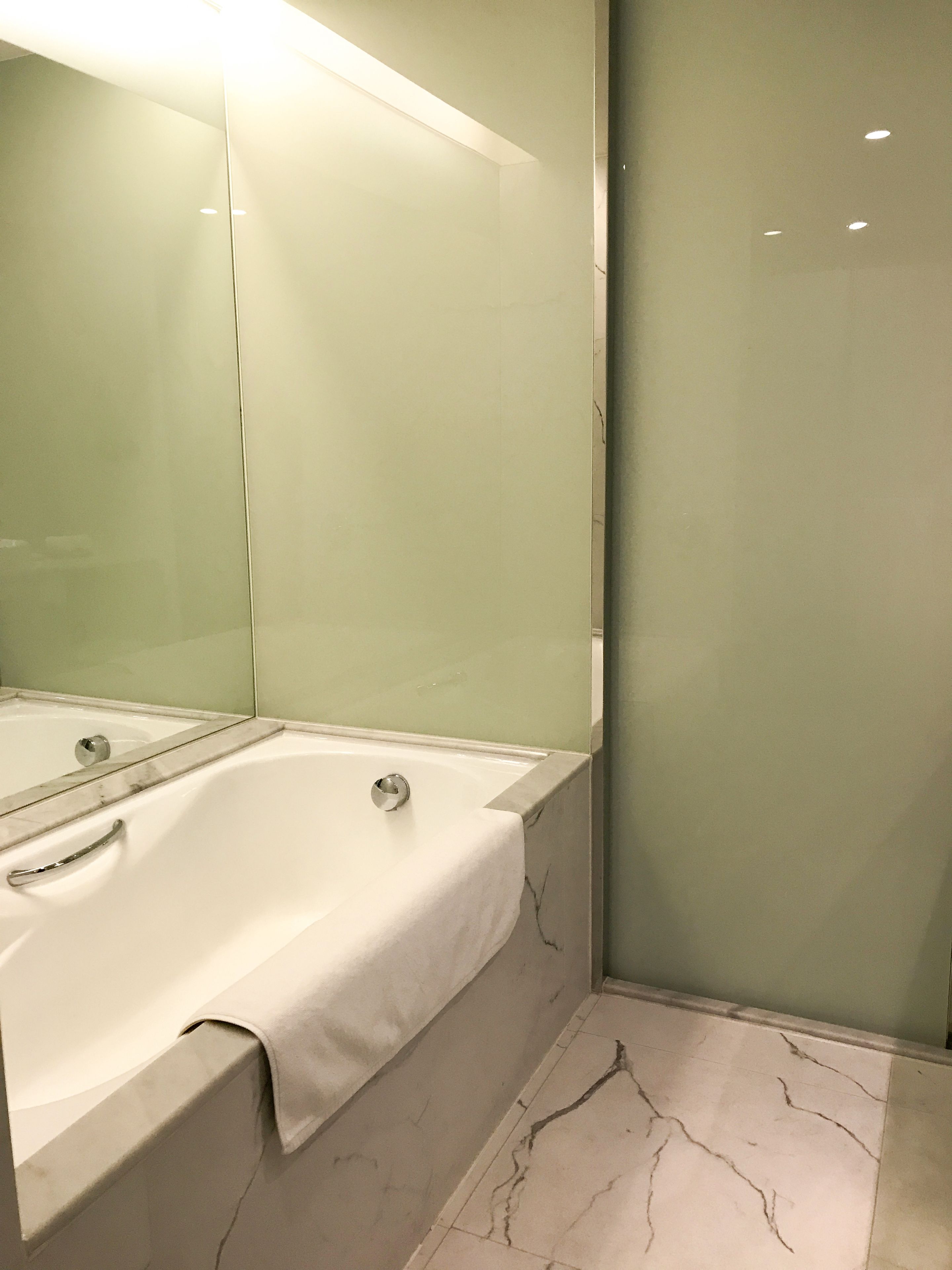 A modern bathroom with a large bathtub, a glass shower enclosure, and a marble floor.