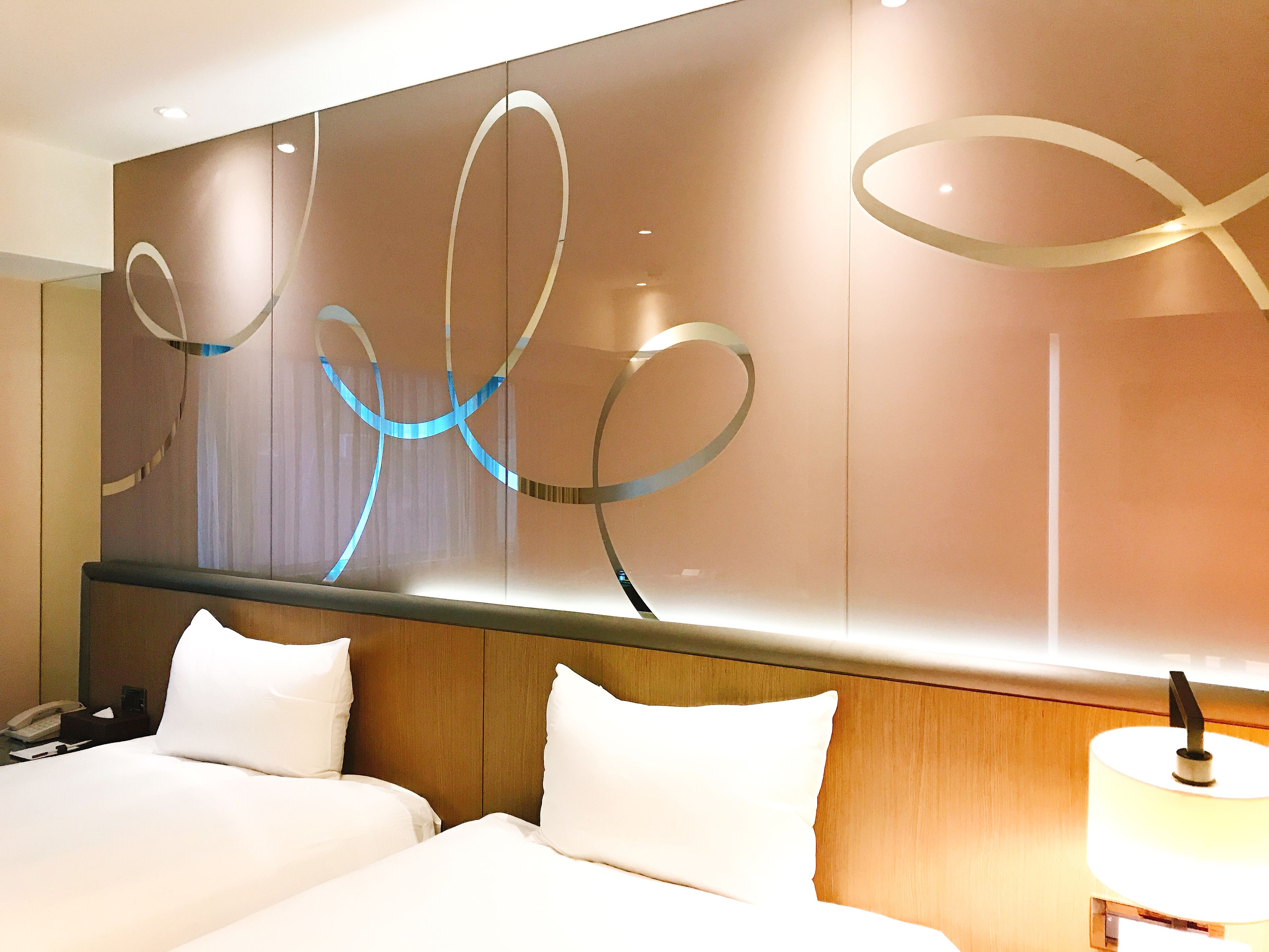 Una habitación de hotel con una cama grande, una mesita de noche, una lámpara y una pared decorada con arte abstracto.