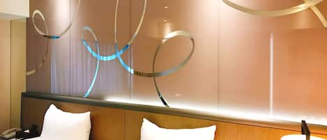 Una habitación de hotel con una cama grande, una mesita de noche, una lámpara y una pared decorada con arte abstracto.