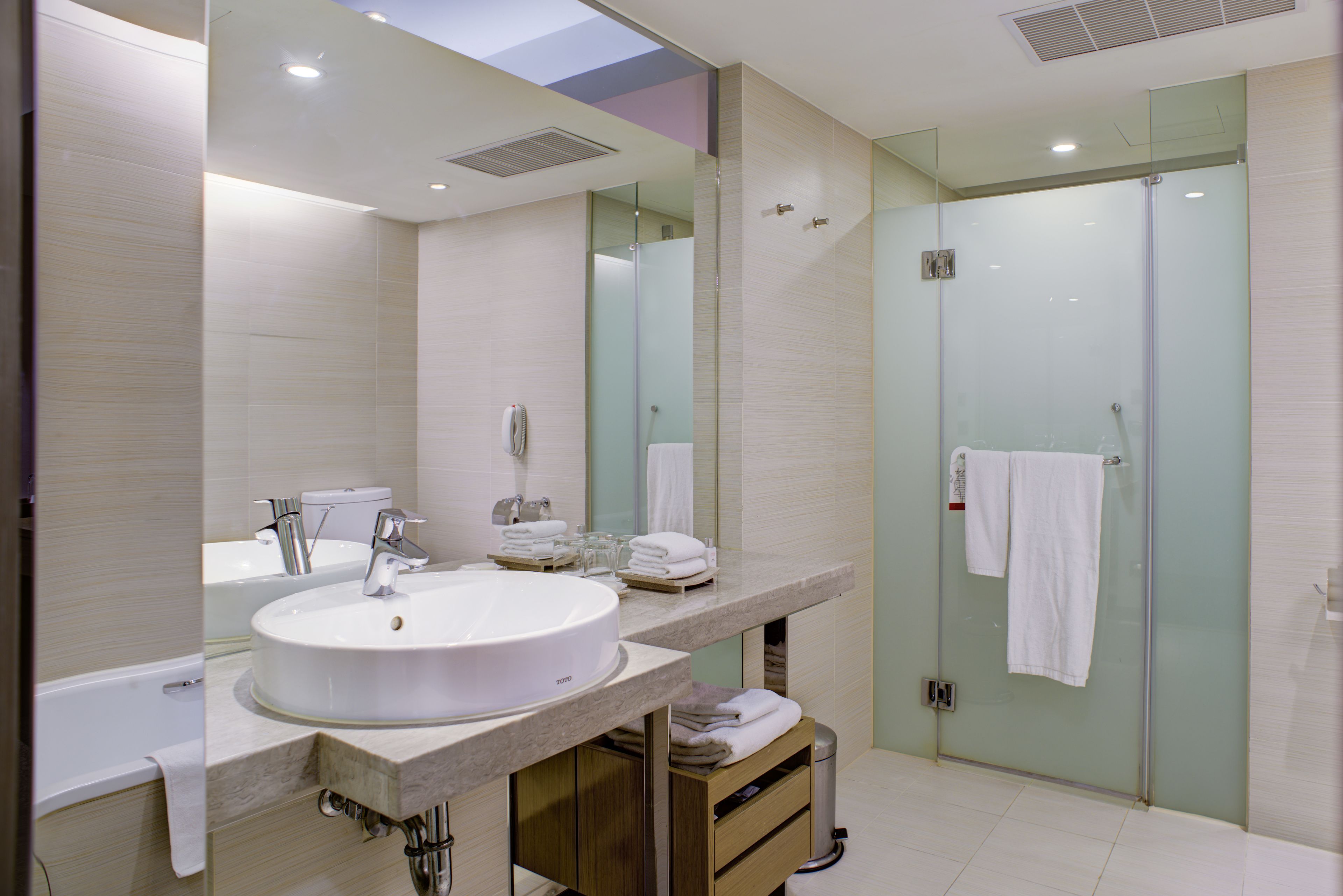 A modern bathroom with a large sink, mirror, and glass shower enclosure.
