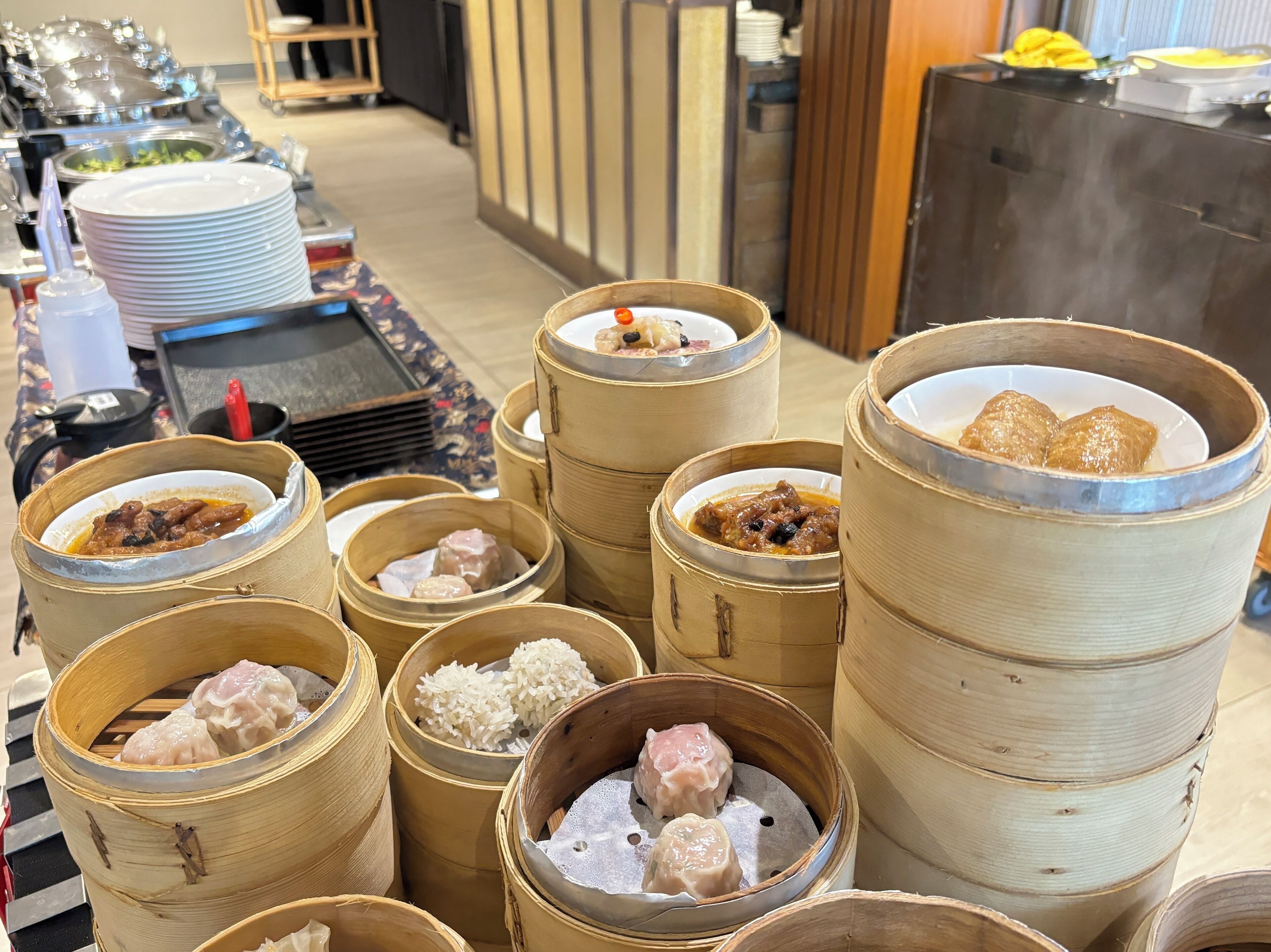 A buffet with various food items, including dumplings and rice, served in bamboo steamers.