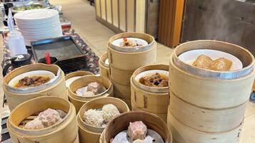 A buffet with various food items, including dumplings and rice, served in bamboo steamers.