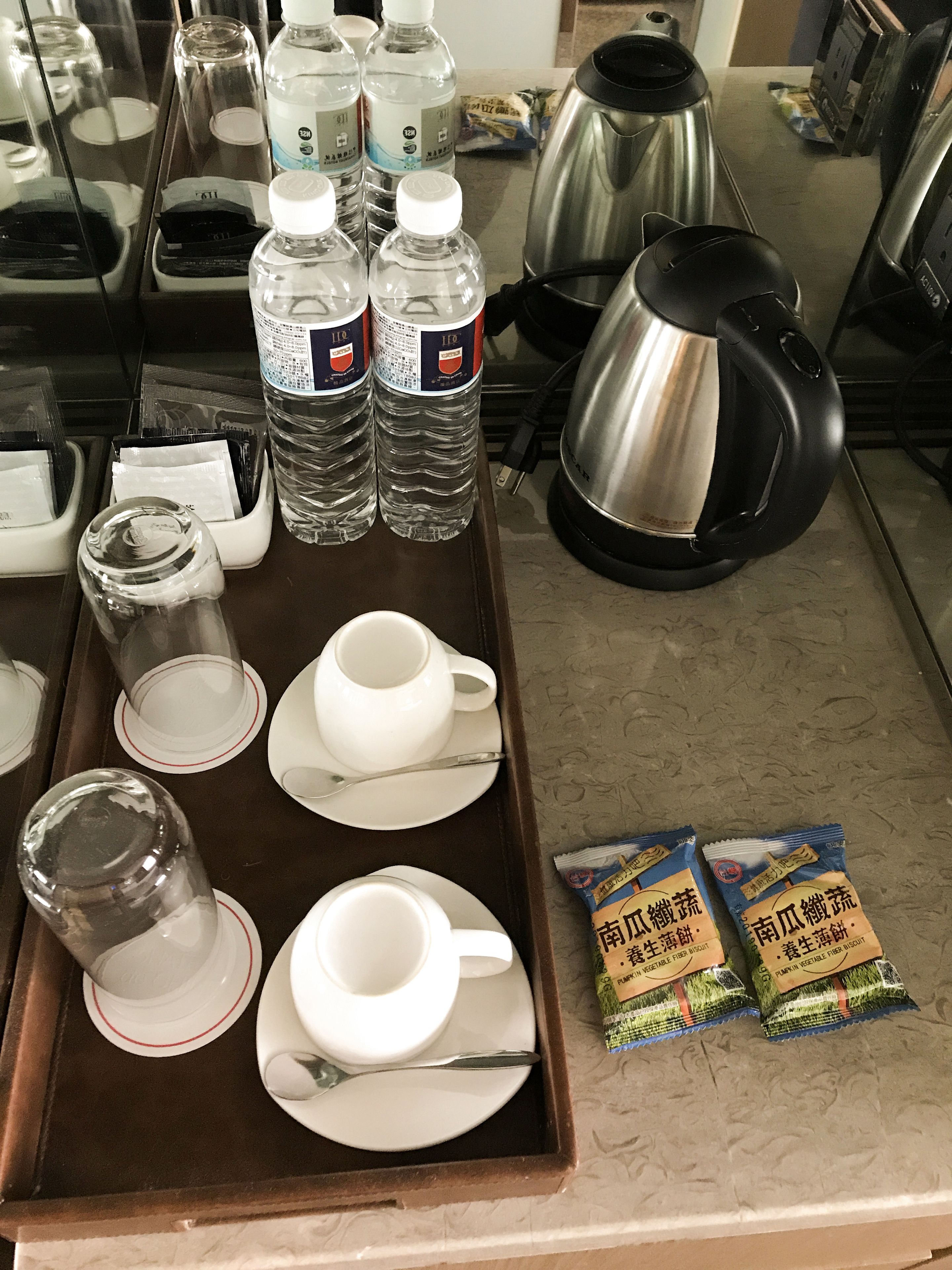 A tray with water bottles, a kettle, and tea packets.