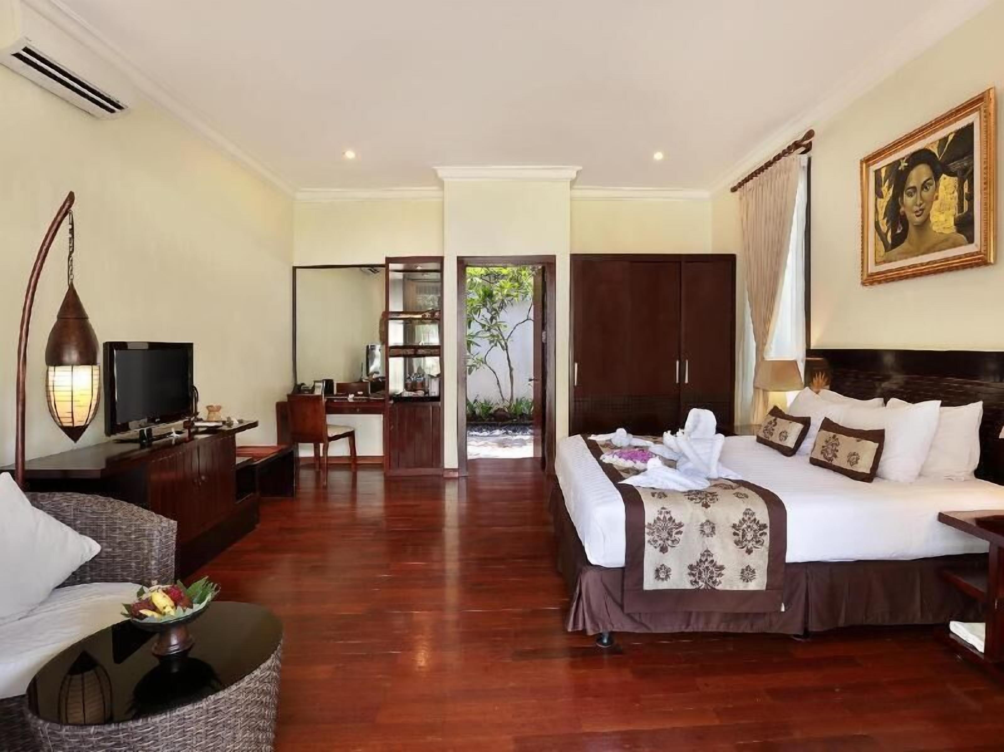 A hotel room with a bed, desk, chair, and a television.