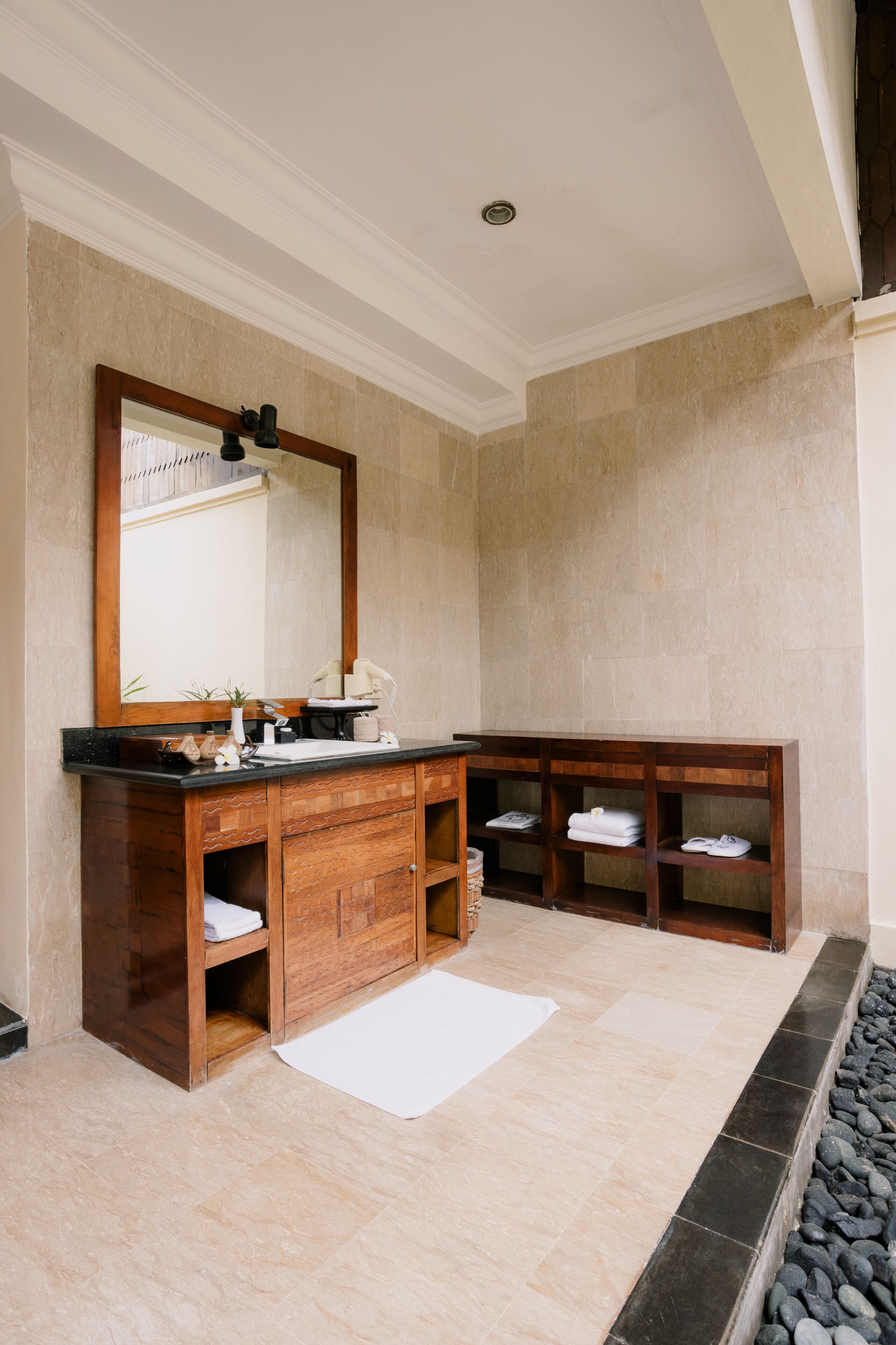 Une salle de bain avec un meuble-lavabo en bois, un grand miroir et un sol carrelé.