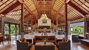 Eine geräumige Lobby mit hohen Decken, einem zentralen Kronleuchter und gemütlichen Sitzbereichen.