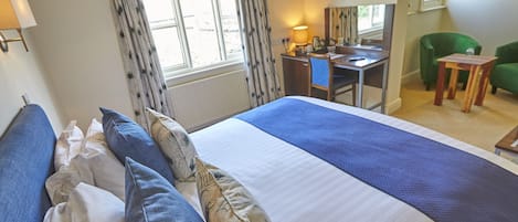 A hotel room with a large bed, a desk, a chair, and a television.