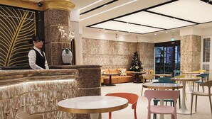 Een moderne hotel lobby met marmeren wanden, een receptiebalie en een kerstboom.