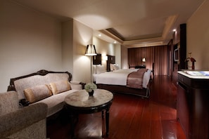 A hotel room with a sofa, a bed, a desk, and a lamp.