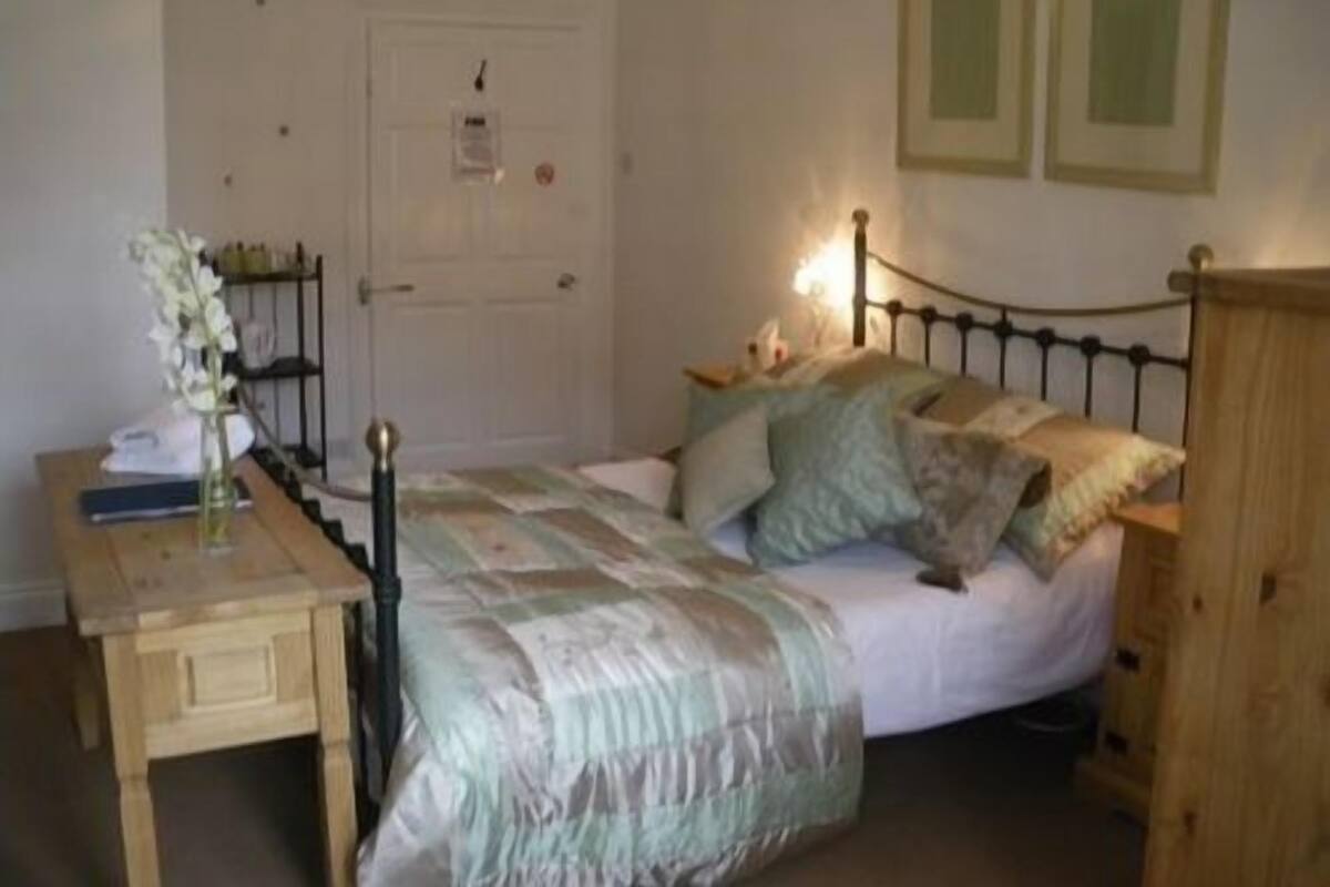 A bedroom with a bed, bedside table, lamp, and a door.