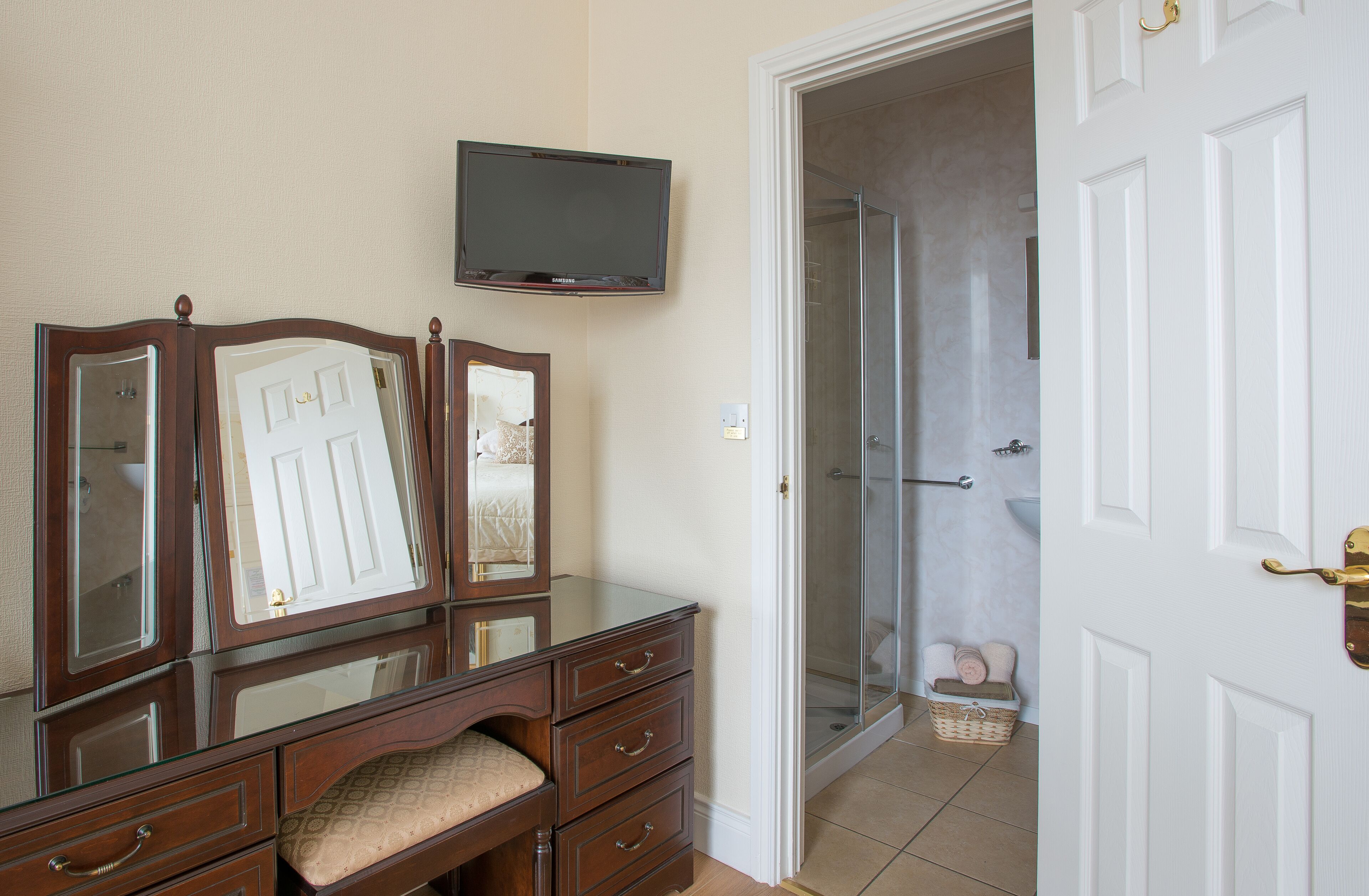 Un dormitorio con tocador, televisor y zona de ducha.